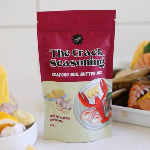 Packaging of 'The Crack Seasoning' seafood boil butter mix with ingredients in the background.