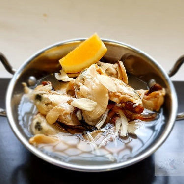 Metallic bowl with seafood and lemon wedge on a dark surface, branded 'Seafood Bazaar'.