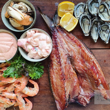 Assorted seafood including fish, prawns, and oysters on a wooden board with 'Seafood Bazaar' branding.