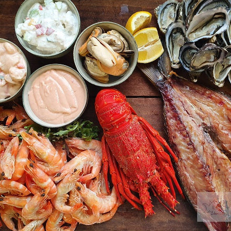 Assorted seafood including oysters, shrimp, and lobster on a wooden surface with a brand label.