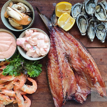 Assorted seafood including fish, prawns, and oysters on a wooden board with 'Seafood Bazaar' branding.