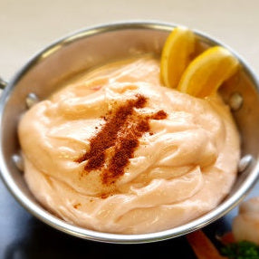 Dish with a creamy pink sauce and lemon slices in a metal bowl on a dark surface.